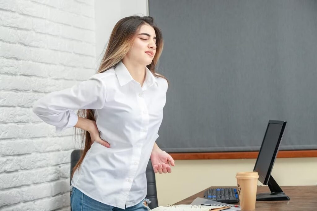 imagem de jovem com dor nas costas depois de ficar muito tempo sentada